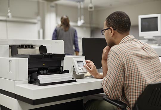 A scanner operator uses a Kodak i5000 Series Scanner to perform high-speed document capture